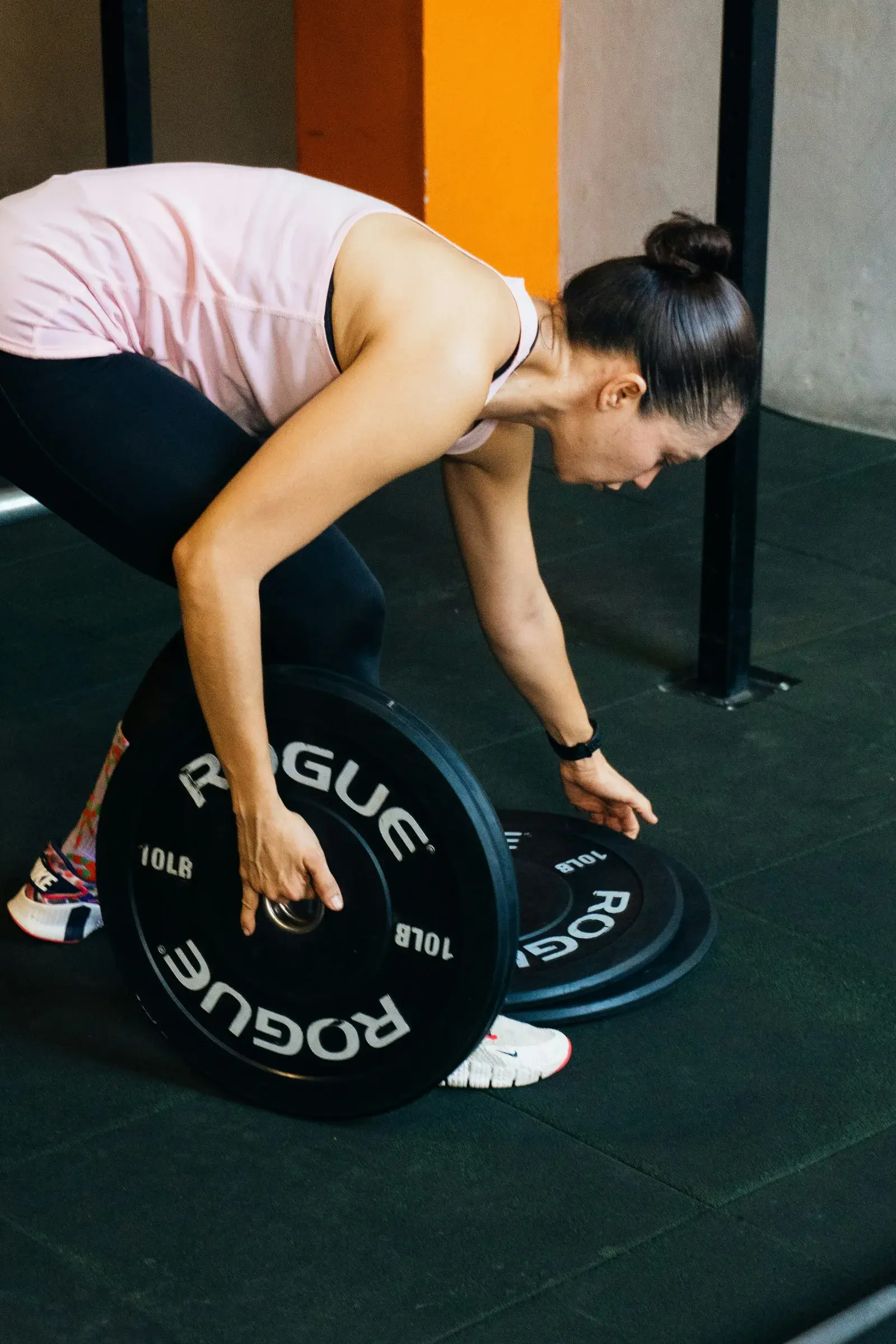 Woman picking up barbell plates